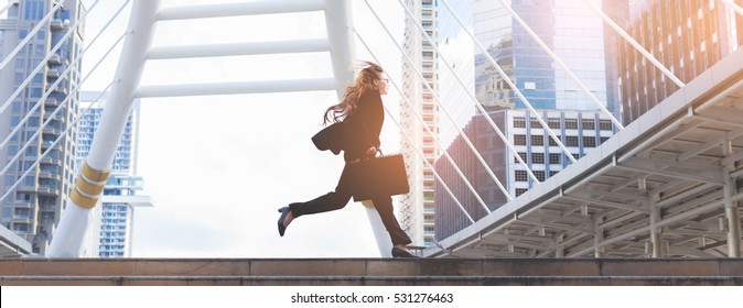 Business Woman  Holding Bag And Running Rapidly To Airport In Formal Suit. In Rush Hour At Stairway In City. Business In The City Concept.