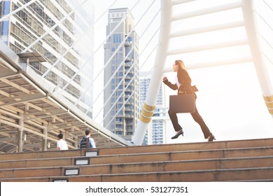 Business woman  holding bag and running rapidly to airport in formal suit. In rush hour at stairway in city. Business in the city concept.