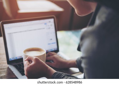 A business woman holding coffee cup while using and typing on laptop in office - Shutterstock ID 628548986