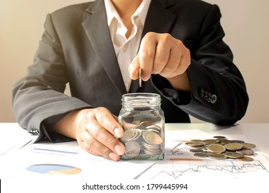 Business Woman Holding A Coin In A Money Jar And Window Light Money Saving Idea.