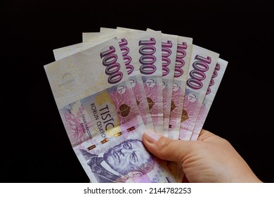 Business woman holding a crown in her hands denomination of a thousand each copy on a black background. The national Czech currency.