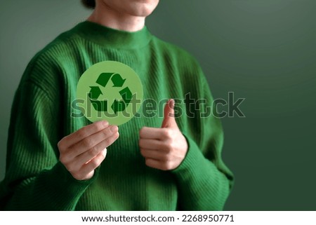 Business woman holding a green paper card with Reduce Reuse Recycle symbol. Company corporate social responsibility and environmental concern. Environmental and Ecology Care Concept. 