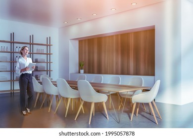 Business Woman holding tablet device and waiting for clients to the modern luxury spa center in downtown to sign the membership contract. Towels and perfume on shelf. Long meeting table with armchairs