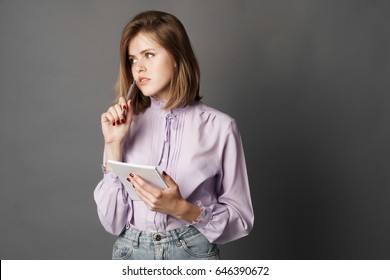 Business Woman Holds A Notebook With A Pen. Something Writes And Thinks. Studio Photography. One On A Gray Background