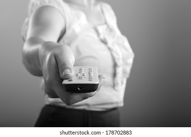 Business woman holds a remote control in her hands with her body out of focus in black and white