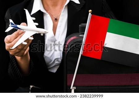 business woman holds toy plane travel bag and flag of United Arab Emirates Flag. 