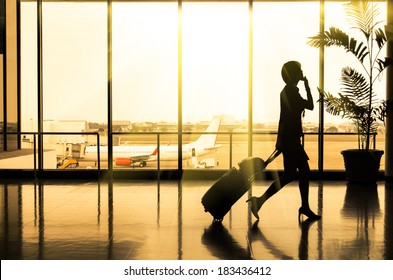 Business Woman At International Airport Moving To Terminal Gate For Airplane Travel Trip - Mobility Concept And Aerospace Industry Flight Connections - Sunshine On Warm Yellow Nostalgic Filtered Look