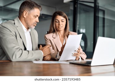 Business woman lawyer manager holding legal documents consulting mature older client at office meeting, two professional executives experts discussing financial accounting papers working together.