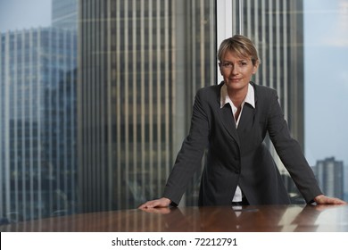 Business Woman Leaning On Chair In Boardroom Looking At Camera