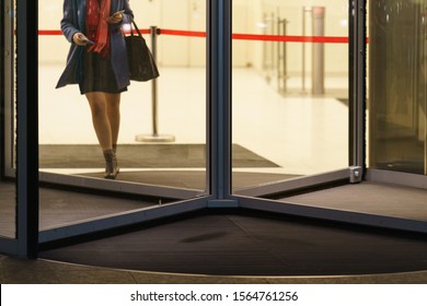 Business Woman Leaving The Office Building. Revolving Door And Herfeet Photography. Urban Office Lifestyles In The End Of Day. Frontal View.