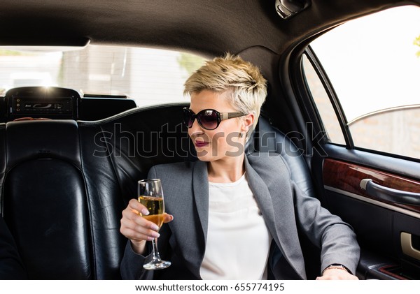Business woman in\
limousine, having\
champagne