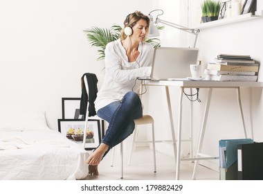 Business Woman Listening Music With Headphones./ Beautiful Mature Business Woman Working With Laptop In Home. 