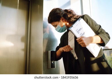 Business Woman  In Medical Face Mask Uses An Elbow To Press The Elevator Button To Prevent The Spread Of The Covid - 19. Office Manadger Back At Work In Office After Quarantine. 
