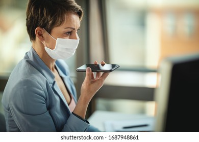 Business woman in a medical protective mask works from home at the computer during self-isolation and quarantine to avoid infection during flu virus outbreak and coronavirus epidemic.