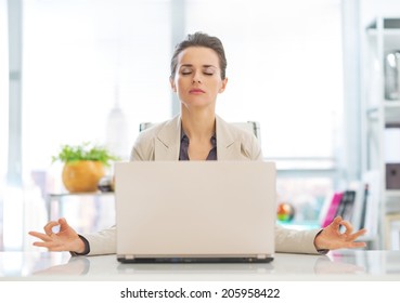 Business woman meditating near laptop
