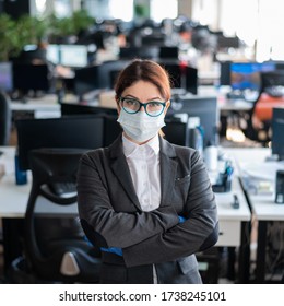 Business Woman In Office In A Protective Mask And Gloves. Female Manager With Glasses And A Suit Works In An Epidemic Of Coronavirus. Caring For The Health And Safety Of Staff. Mask Mode.