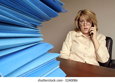 Business Woman On Phone With Large Pile Of File Folders