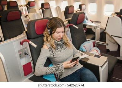 Business Woman Passenger Listening To Music And Relaxing During The Flight By Airplane In First Class. Comfortable, Luxury Travel
