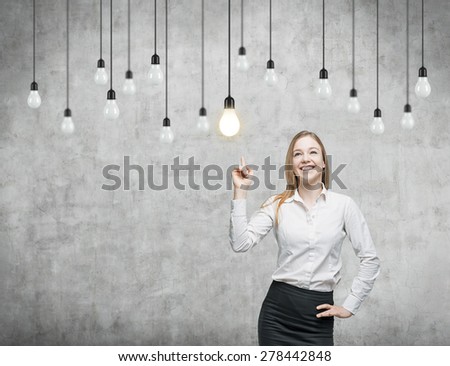 Business woman is pointing out the light bulbs. The concept of the innovative business strategy. Concrete background.