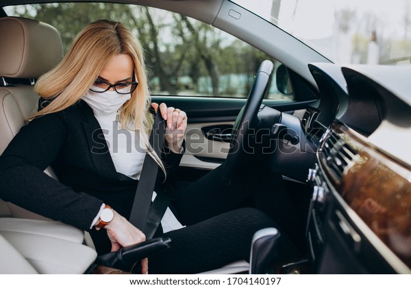 Business
woman in protection mask sitting inside a
car