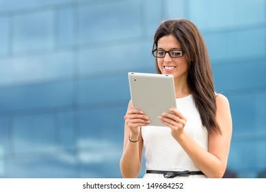 Business Woman Reading Corporation On Tablet Pc Computer Outside Corporate Financial Building. Happy Caucasian Hispanic Female Executive Or Assistant Doing Her Job Using Digital Technology.