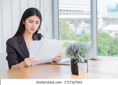 Business Woman Reading Documents Or Managing Finances, Reviewing Company Bank Accounts Or Paying Taxes Online On Modern Office. Model Asian. Tax, Accounting, Statistics And Analytic Research Concept