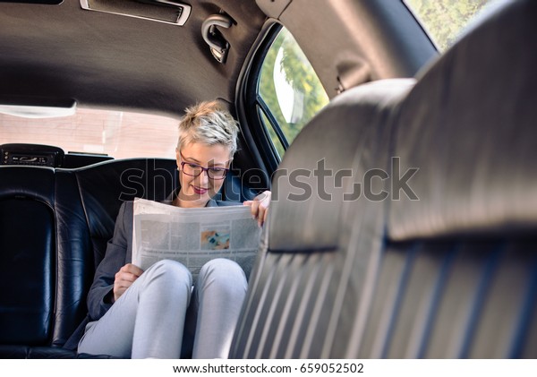 Business woman\
reading newspaper in\
limousine
