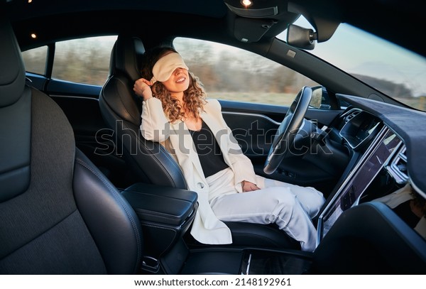 Business woman\
resting on driver\'s seat in automobile with bandage for sleep while\
her car moving on full autopilot. Modern opportunity to rest while\
vehicle driving\
independently.