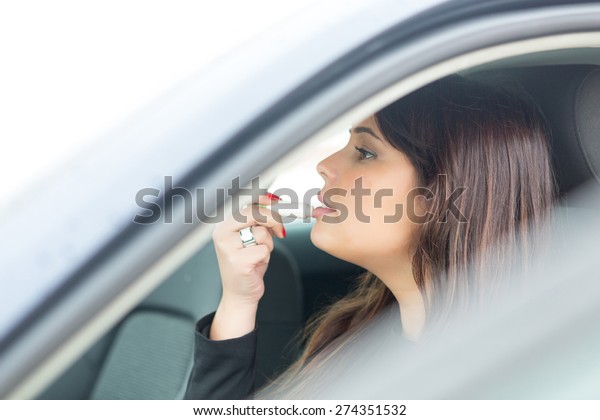 Business woman retouching her makeup while\
stopped in the traffic