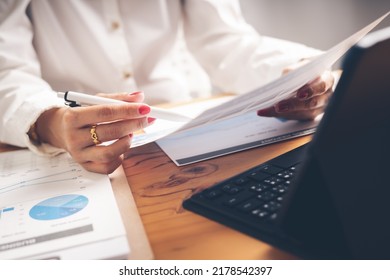 Business Woman Reviewing Data In Financial Charts And Graphs On Wooden Desk In Office And Business Working, Tax, Accounting, Statistics And Analytic Research Concept