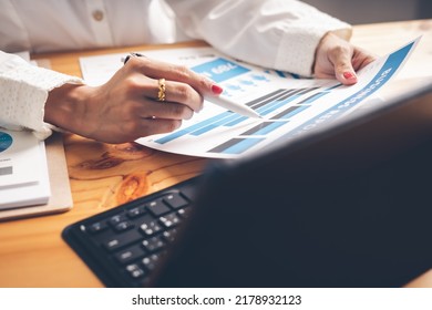 Business Woman Reviewing Data In Financial Charts And Graphs On Wooden Desk In Office And Business Working, Tax, Accounting, Statistics And Analytic Research Concept