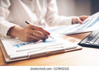 Business Woman Reviewing Data In Financial Charts And Graphs On Wooden Desk In Office And Business Working, Tax, Accounting, Statistics And Analytic Research Concept