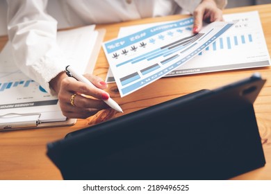 Business Woman Reviewing Data In Financial Charts And Graphs On Wooden Desk In Office And Business Working, Tax, Accounting, Statistics And Analytic Research Concept