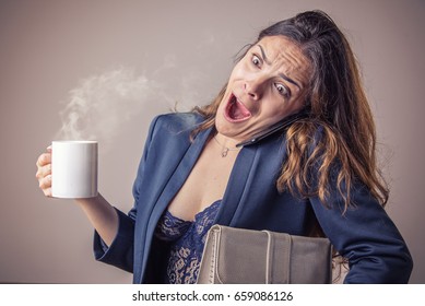 Business woman running late, holding her coffee, cell phone and files