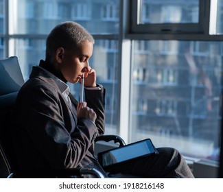 Business woman with short hair sits by the window and writes on a digital tablet with a stylus pen - Shutterstock ID 1918216148