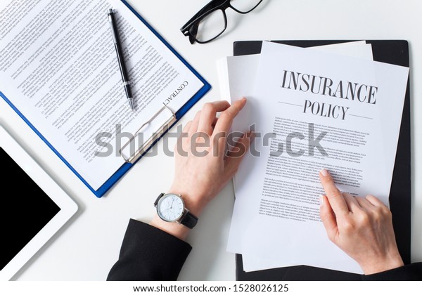 Business woman showing insurance document over\
white desk at office