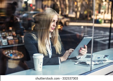 Business woman sitting in cafe and using tablet pc and drinking coffee - Powered by Shutterstock