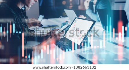 Business woman sitting front laptop computer with financial graphs and statistics on monitor. Double exposure. Wide