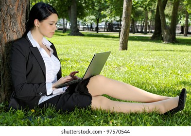 Business Woman Sitting On Green Grass And Working On Laptop In The Park