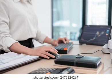 Business woman is sitting on her working desk in the office. She is stressed and disappointed at the stock trading market value as she is staring computer screen looking at charts and data analysis. - Powered by Shutterstock