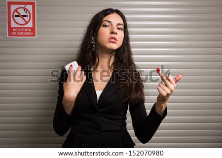 Business woman smokes against signs prohibiting smoking