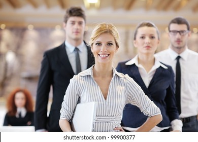 Business Woman Standing With Her Staff In Background At Modern Bright Office Conference Room