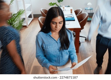 Business woman stands still while colleagues rush past, motion blur in office