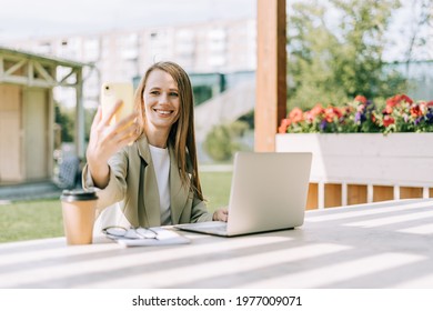 Business Woman In Suit Taking A Selfie On Cellphone And Working At Laptop Sit Down On Bench Outside. Happy Student Lady Girl Having A Video Chat With Phone, Distance Learning And Online Education.