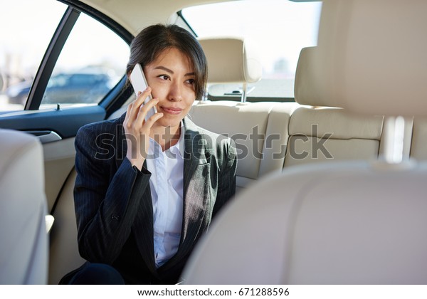 Business\
woman in suit talking by the phone in the\
car