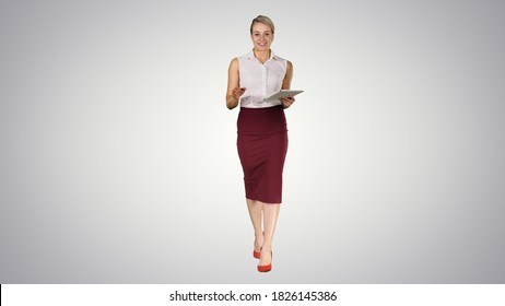 Business Woman With Tablet Walking And Talking To The Camera On Gradient Background.