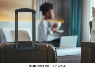 A business woman tourist drinks coffee and rests, looking at the beautiful view with her luggage in the hotel bedroom after check-in. The concept of travel and vacation