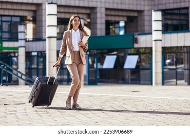 Business woman travel to airport, hotel or office. Portrait of young professional walking in city street with suitcase bag - Powered by Shutterstock