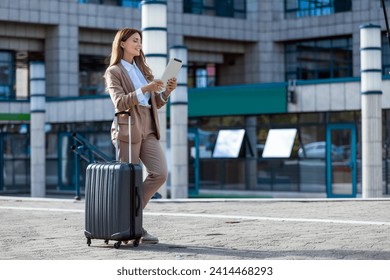 Business woman travel to airport, hotel or office. Portrait of young professional walking in city street with suitcase bag using a digital tablet while waiting a driver - Powered by Shutterstock