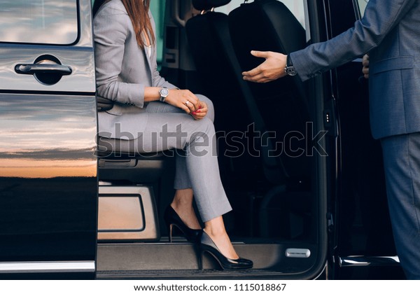 Business woman travelling in vip car transfer. Driver\
helping woman to get outside the car. Gentleman give a hand to the\
lady at the car